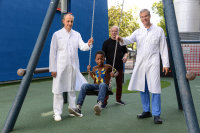 Phillipe kann wieder lachen: Phillipe (10) mit (v.l.) Prof. Univ. Dr. Eugen Sandica, Dr. Klaus Kogelmann und Prof. Dr. Stephan Schubert auf dem Spielplatz des Kinderherzzentrums am Herz- und Diabeteszentrum NRW, Bad Oeynhausen (Foto: Marcel Mompour).