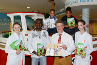 Endlich da: Yvonne Brocks (lks.), Bernhard Silaschi und Deborah Grisse (re.) überreichen die ersten druckfrischen Exemplare des neuen Kinderbuchs an Frederick Kwaku Schildhauer (2.v.l.) und seine Söhne (oben v.l.) Darius (7) und Raimund (13) (Foto Armin Kühn).