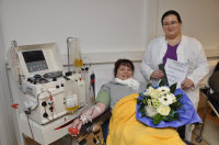 Gratulation zur 101. Blutplättchenspende: Anett Windelband (m.) nimmt von Martina Schumann (r.) vom Uni.Blutspendedienst OWL einen großen Blumenstrauß, eine Ehrenurkunde und ein kleines Geschenk entgegen (Foto Armin Kühn).